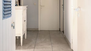 A hallway with a white door, a white cabinet with drawers, and a blue wall-mounted light fixture.