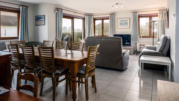 A spacious living room with a dining area, large windows, and a sofa.