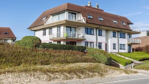 A two-story house with a balcony, a staircase, and a well-maintained garden.