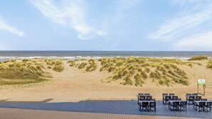 Une terrasse au bord de la plage, avec des sièges en plein air et une vue sur l’océan.