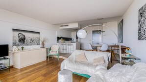 Un salon moderne avec un canapé, un pouf et un téléviseur à écran plat.