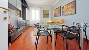 A modern living room with a glass dining table, black chairs, a sofa, and artwork on the walls. - Una finestra sulla cupola di San Pietro (Rome)