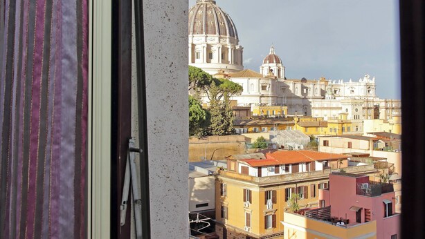 A view of a cityscape with a prominent domed building and surrounding residential buildings. - Una finestra sulla cupola di San Pietro (Rome)