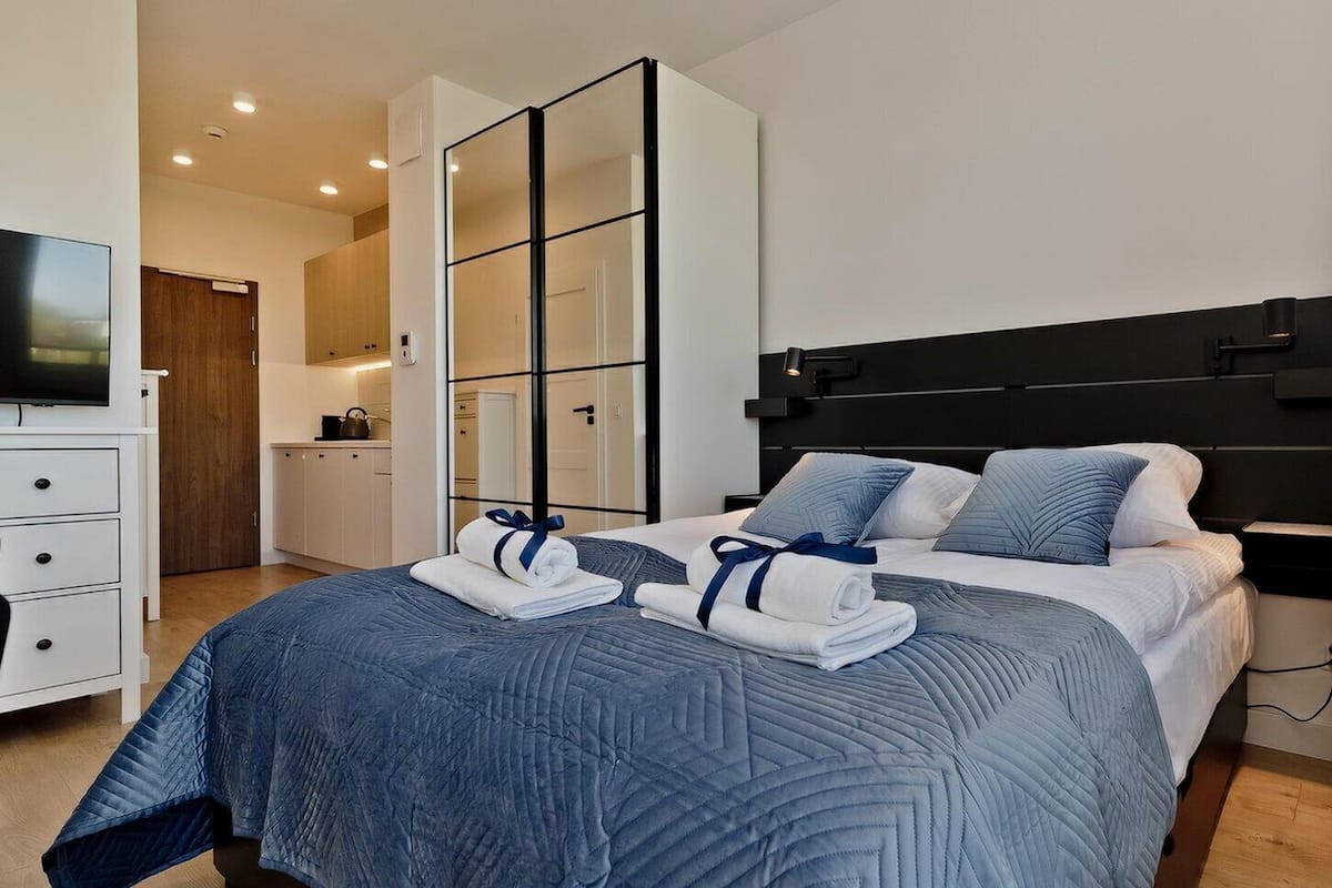Une chambre d’hôtel moderne dotée d’un grand lit, d’une télévision et d’un espace séparé aménagé en coin cuisine.