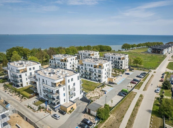 Un moderno complejo de apartamentos con varios edificios, un estacionamiento y vista al mar.