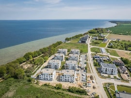 Vista aérea de una zona residencial costera con modernos edificios de apartamentos, un puerto deportivo y una vista despejada del mar.
