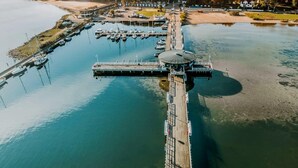 An aerial view of a marina with boats docked, a pier extending into the water, and a building with a circular roof. - Apartamenty NEXO - Puck by Q4Apartments  (Puck)