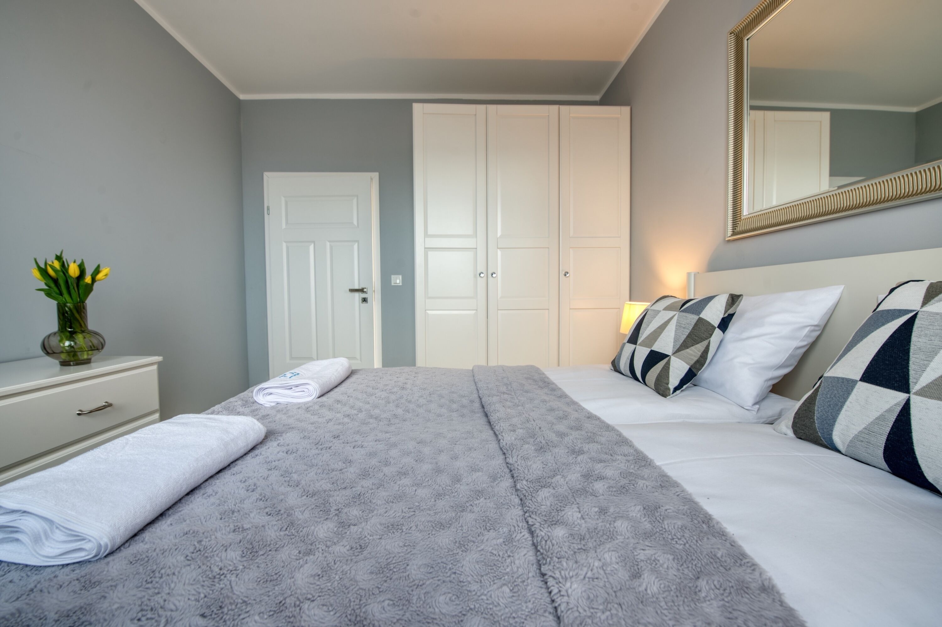 Un dormitorio con cama, cómoda, espejo y puerta.