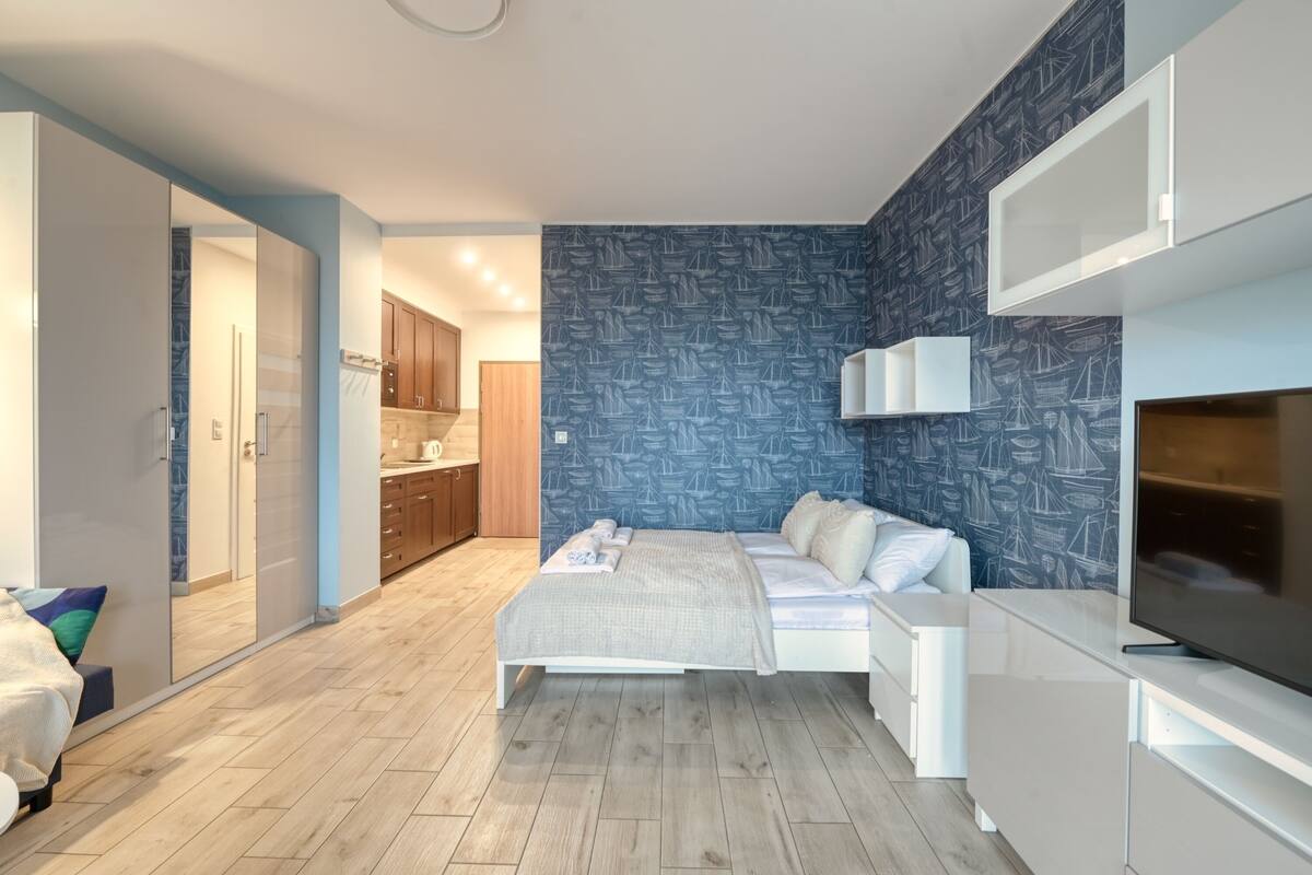 Une chambre à coucher moderne avec un lit, des tables de chevet, un téléviseur et une armoire.