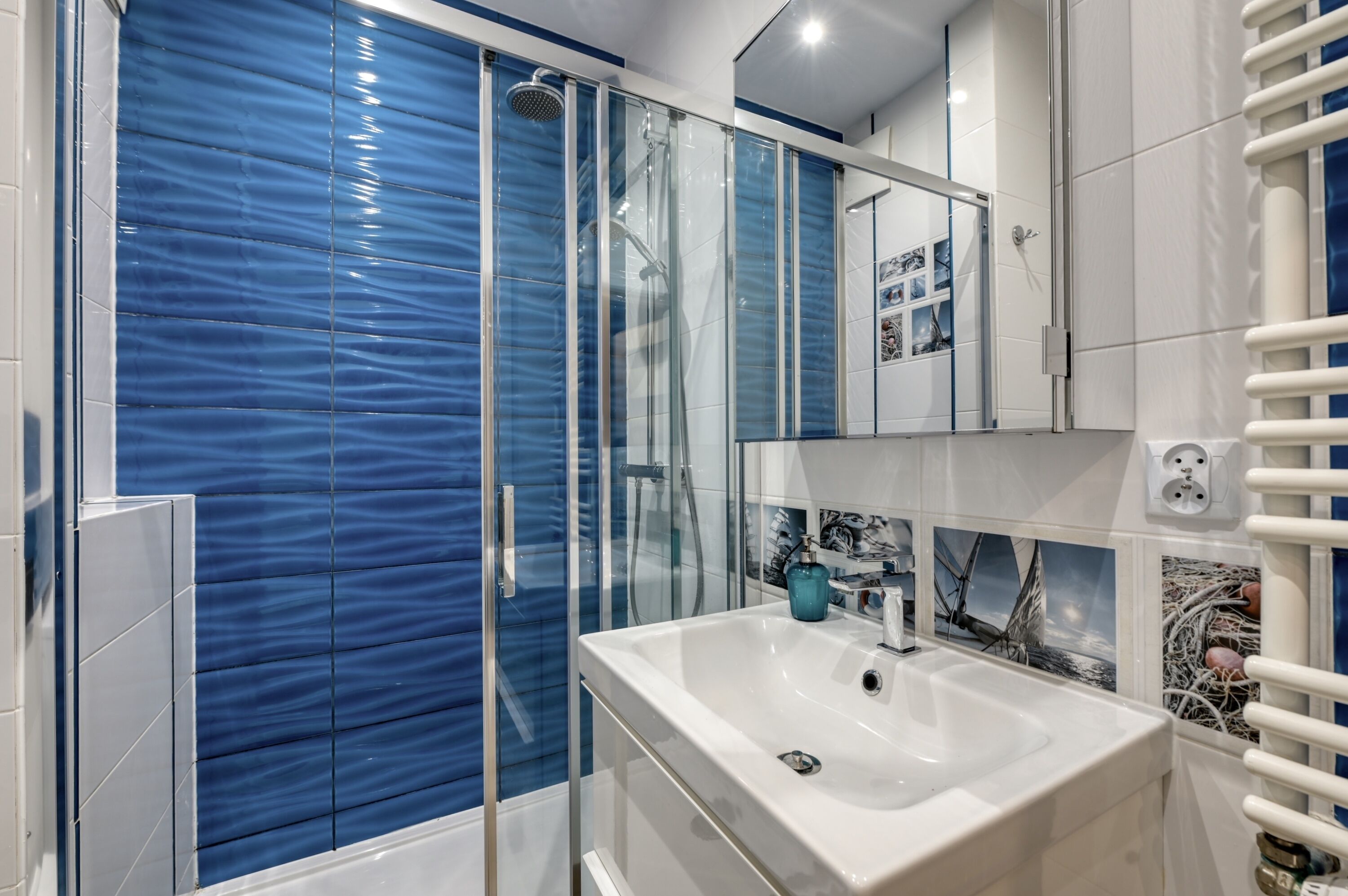 Un baño con cabina de ducha de vidrio, un lavamanos blanco y un espejo encima.