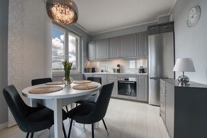 Una cocina moderna con armarios grises, un refrigerador de acero inoxidable y un comedor con una mesa redonda y sillas.