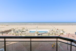 Uitzicht op een strand met een zwembad, een promenade en een controle toren.