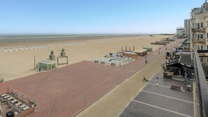 Blick auf einen Strand mit Parkplatz, einer Statue und einem Gebäude mit einem Schild.