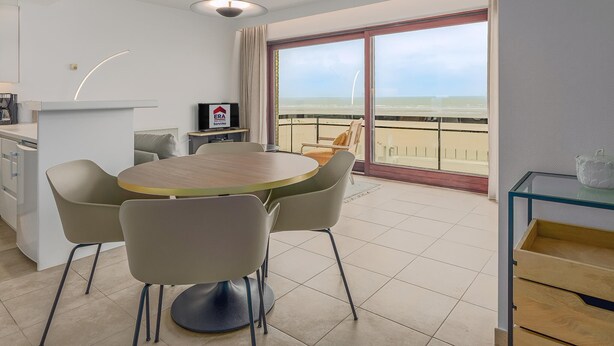 Ein modernes Zimmer mit Balkon, Essbereich und Fernseher.