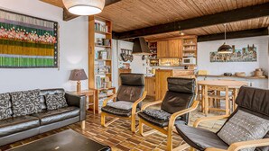 En hyggelig stue med sofa, stole, et sofabord og en reol.