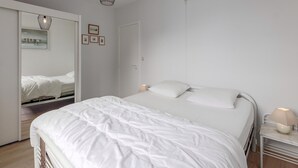 Een moderne slaapkamer met een groot bed, een bedlampje, een spiegel en een kledingkast.