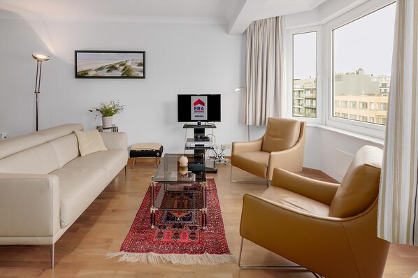 A modern living room with a sofa, armchair, and a TV on a stand.