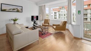 Een moderne woonkamer met een bank, twee fauteuils, een televisie en een plant.
