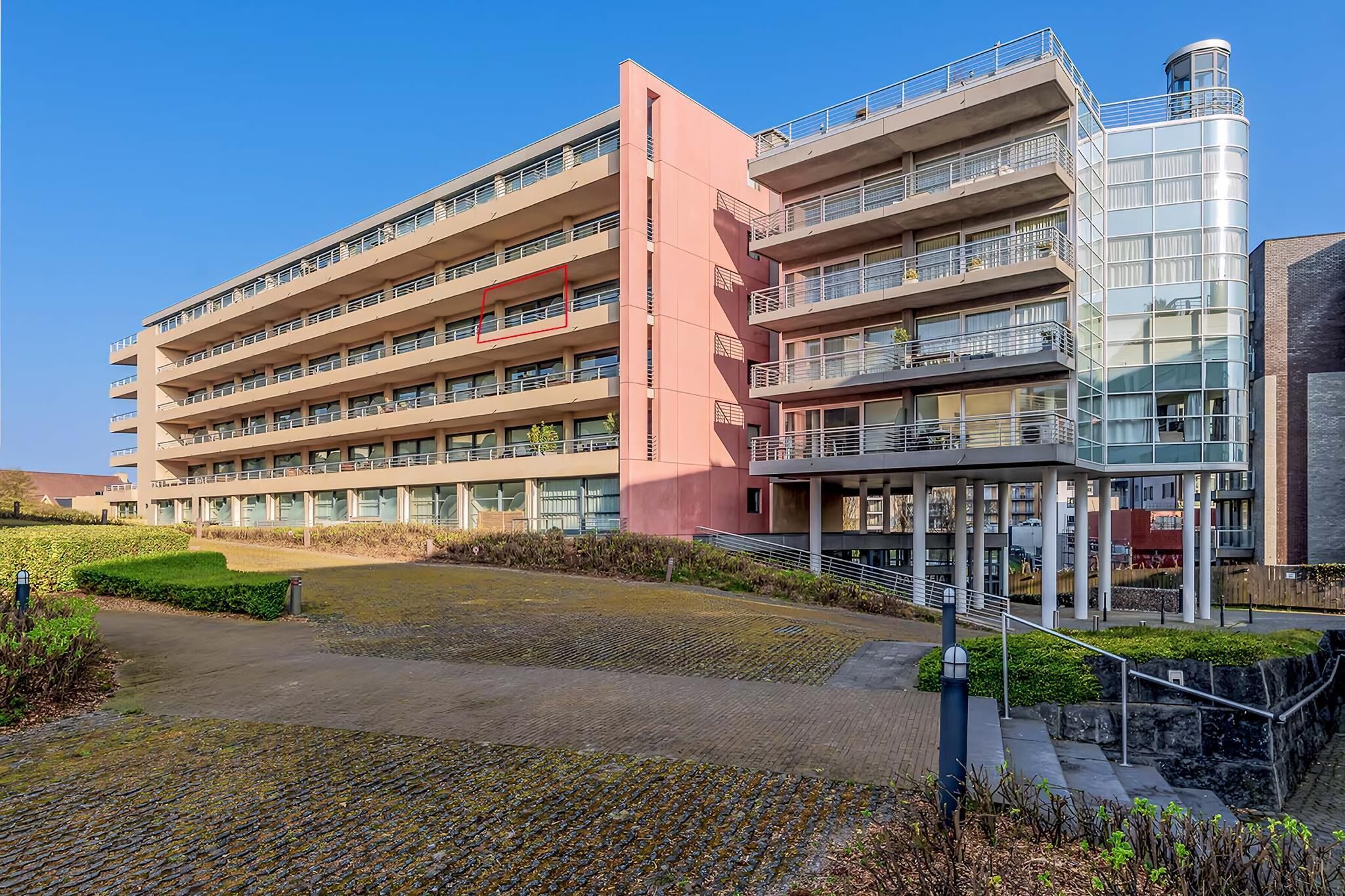 Et moderne hotel med flere etager, med altaner på hver etage og en central gårdsplads.