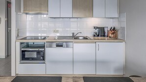 Une cuisine moderne avec des meubles blancs, un four à micro-ondes encastré et une machine à café.