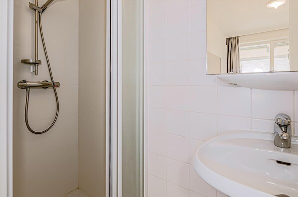 A bathroom with a shower, a sink, and a mirror.