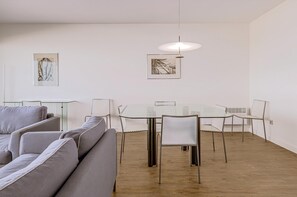 A modern living room with a glass dining table, grey sofas, and minimalist decor. - Gray D´Albion A53 + G (Oostduinkerke)