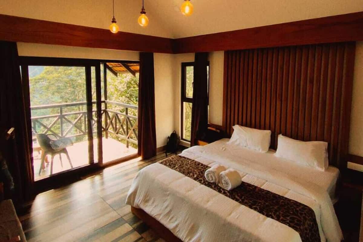 Ein Schlafzimmer mit einem großen Bett, Holzbalken und Blick durch die Glasdoor.
