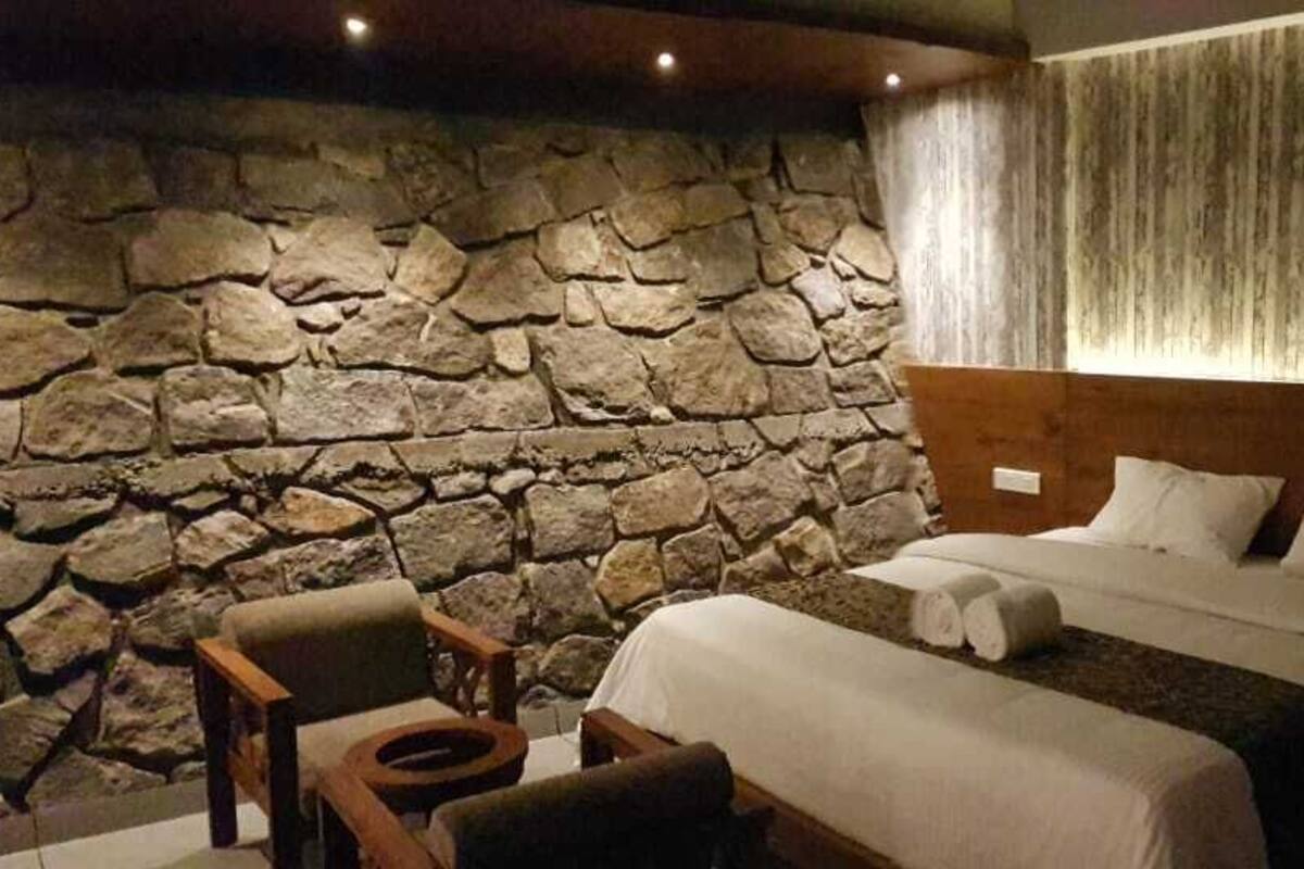 Ein Schlafzimmer mit Stehwand, einem Bett mit weißer Bettwäsche und einem hölzernen Kopfteil.