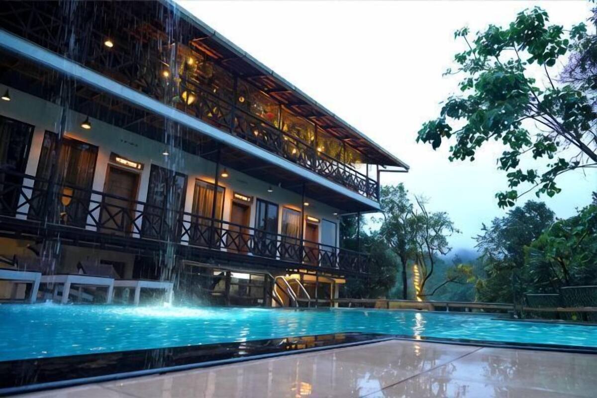 Ein Hotel mit Pool, einem Balkon im zweiten Stock und einem Wasserfall.