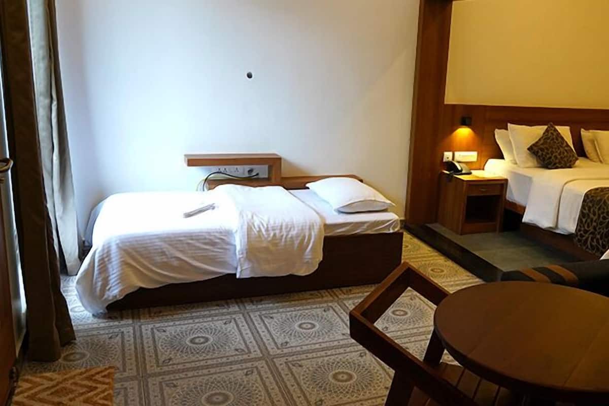 Ein Hotelzimmer mit zwei Betten, einem kleinen Tisch und einer Couch.