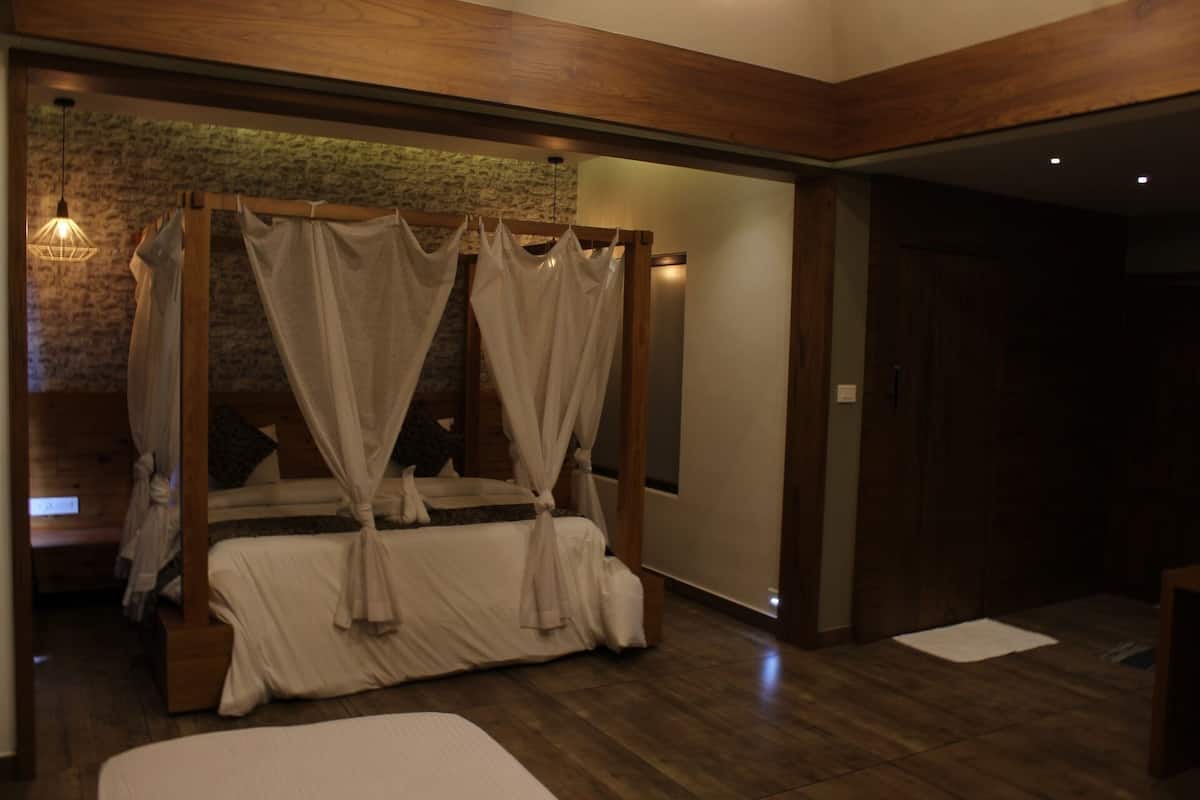 Ein Schlafzimmer mit Himmelbett, Holzboden und Steinwand.