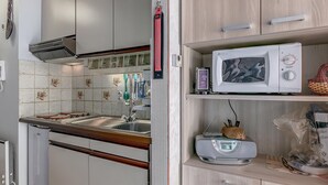 A kitchen with a microwave, toaster, and a small refrigerator.