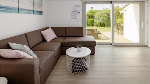 Una sala de estar moderna con un sofá modular, una mesa de centro redonda y un ventanal corredero que da a un patio exterior.