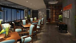 A modern interior with tables and chairs, a bookshelf, and a large window. - James Joyce Coffetel Beijing Yizhuang East Rongjing Street Metro Station (Beijing)