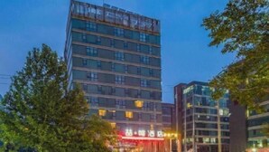 A multi-story hotel with a modern design, featuring balconies on the upper floors and a prominent entrance with illuminated signage. - James Joyce Coffetel Beijing Yizhuang East Rongjing Street Metro Station (Beijing)