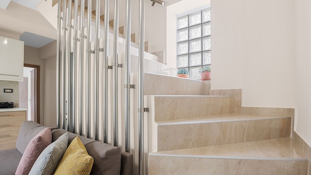 Un intérieur moderne avec un escalier, un canapé agrémenté de coussins à motifs et une fenêtre offrant une vue agréable.