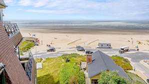 A beachside view with a parking area, a building with a sloped roof, and a clear sky. - LONG ISLAND 19, B52 + G (Oostduinkerke)