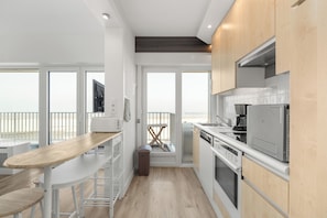 Una cocina moderna con armarios blancos, una mesa de comedor de madera y vistas al exterior.