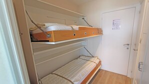 A room with a bunk bed, a door, and a wooden floor.