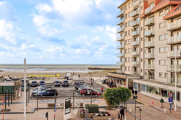 A coastal hotel with multiple floors, a parking area, and a view of the beach.