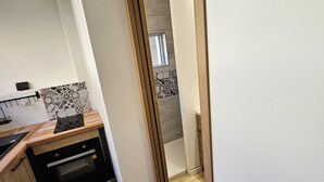 A modern kitchen with wooden flooring, a built-in oven, and a backsplash with a geometric pattern. - Superb cosy studio for 2 people - Luchon center (Bagnères-de-Luchon)