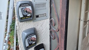 A security keypad and card reader mounted on a textured wall near a metal gate. - Superb cosy studio for 2 people - Luchon center (Bagnères-de-Luchon)