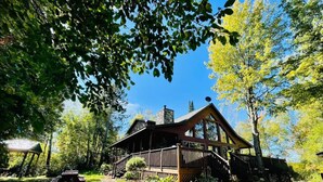 A cabin with a porch, surrounded by trees and a picnic table. - Private Island on Lake Winter (Winter)