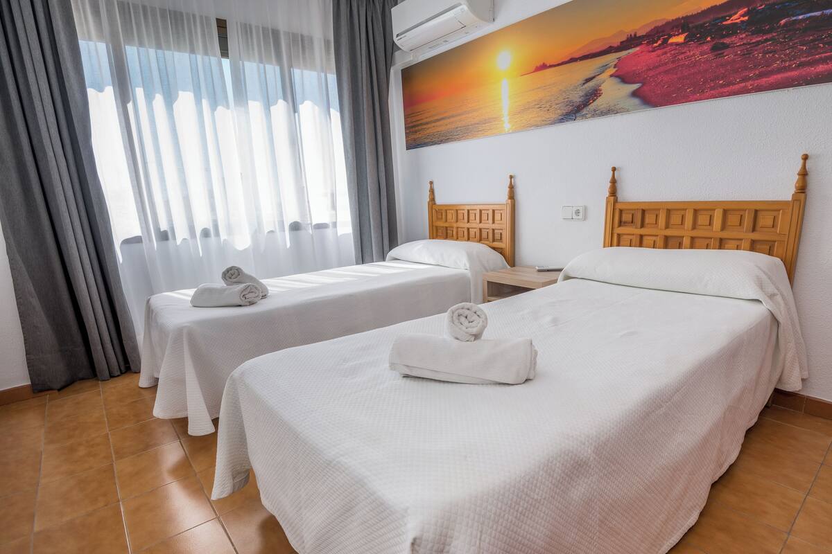Ein Hotelzimmer mit zwei Betten, jeweils mit einem Holzkopfstück, weißer Bettwäsche und Handtüchern.