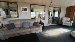 A living room with a beige sofa, a patterned armchair, a coffee table, and a lamp.