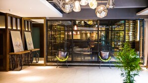 A modern interior with a seating area, a display of artworks, and a wine rack. - James Joyce Coffetel (Chengdu)