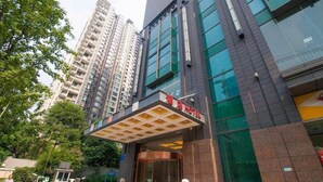 A hotel entrance with a modern facade, a red carpet, and a security booth. - James Joyce Coffetel (Chengdu)