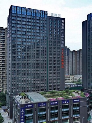 A high-rise building with multiple floors, featuring a modern architectural design with a prominent glass facade. - James Joyce Coffetel (Chengdu)