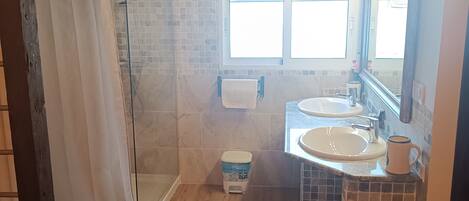 Ein Badezimmer mit Dusche, zwei Waschbecken, Toilette und Fenster.