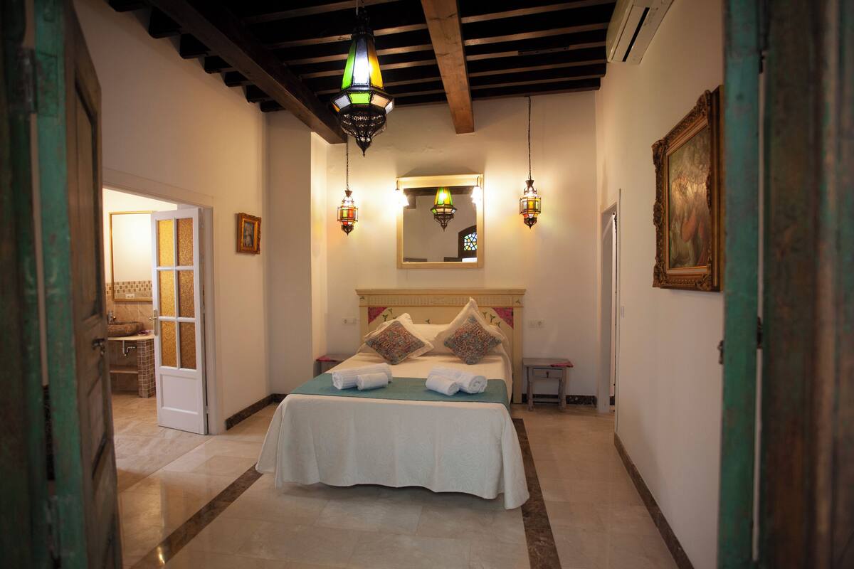 A hotel room with a bed, a mirror, and a painting on the wall.